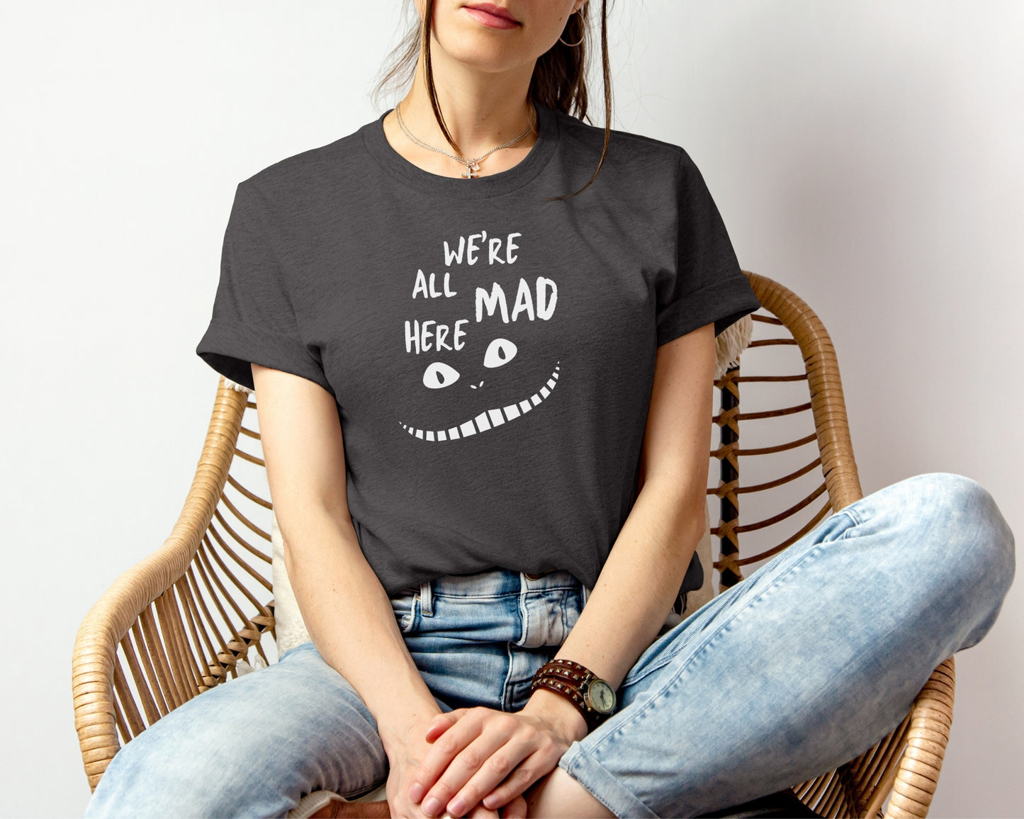 female model wearing bella and canvas 3001 t-shirt in dark grey heather with 'we're all mad here' cheshire cat inspired print on chest