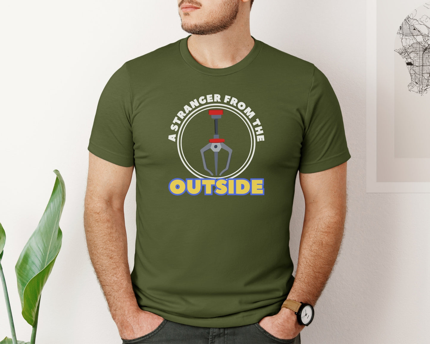 male model wearing bella and canvas 3001 t-shirt in olive with 'a stranger from the outside' grabber claw graphic on chest inspired by Toy Story