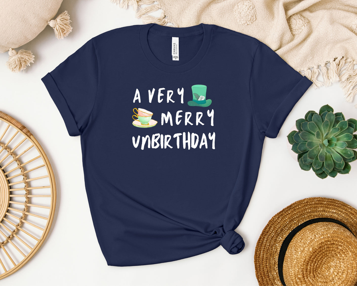 Bella and Canvas 3001 T-Shirt in navy laid flat, with a disney/Alice in Wonderland inspired 'a very merry unbirthday' design on chest