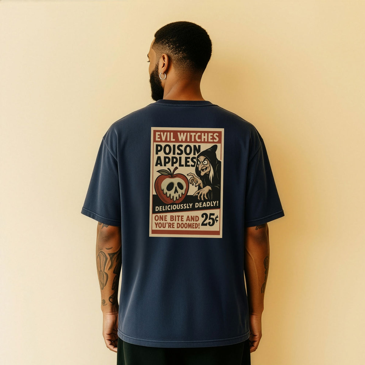A man viewed from the back wearing a navy blue t-shirt with a large vintage-style Halloween graphic on the back. The graphic features a skull in a pumpkin, a witch, and text reading 'EVIL WITCHES POISON APPLES DELICIOUSLY DEADLY! ONE BITE AND YOU'RE DOOMED! 25¢'.