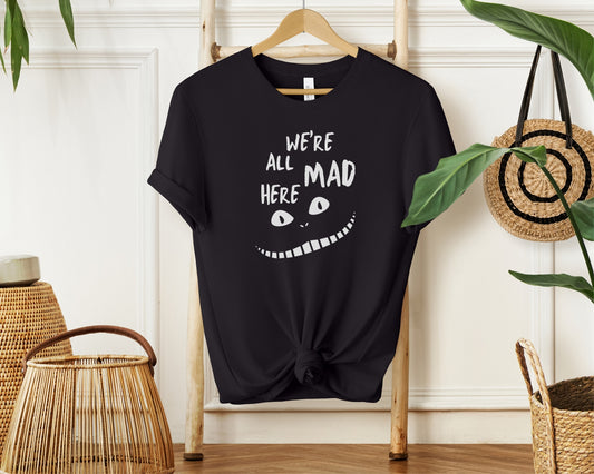 Hanging bella and canvas 3001 t-shirt in black with 'we're all mad here' cheshire cat inspired print on chest